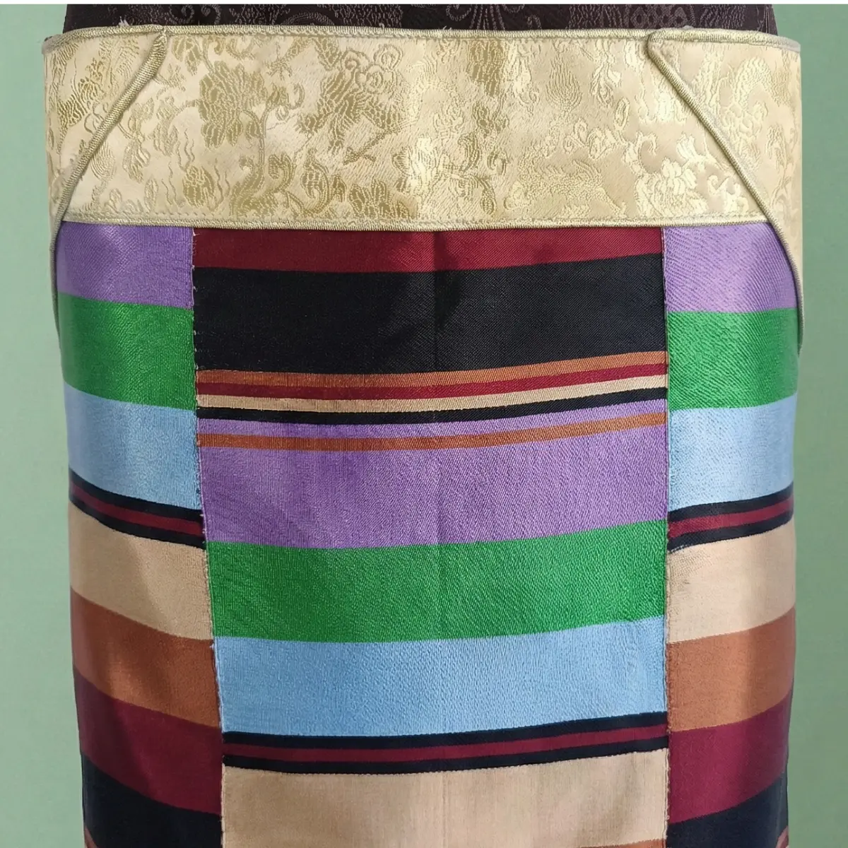 Close-up of light gold border and multicolour stripes on Pangden apron