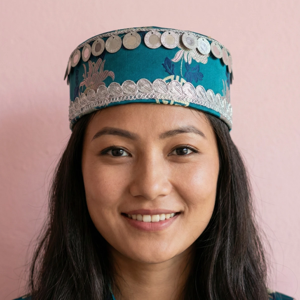Girl wearing Teal Tamang topi showing hand-applied silver coins and scattered motis on woven Tash Kuchin base Girl wearing Teal Tamang topi showing hand-applied silver coins and scattered motis on woven Tash Kuchin base