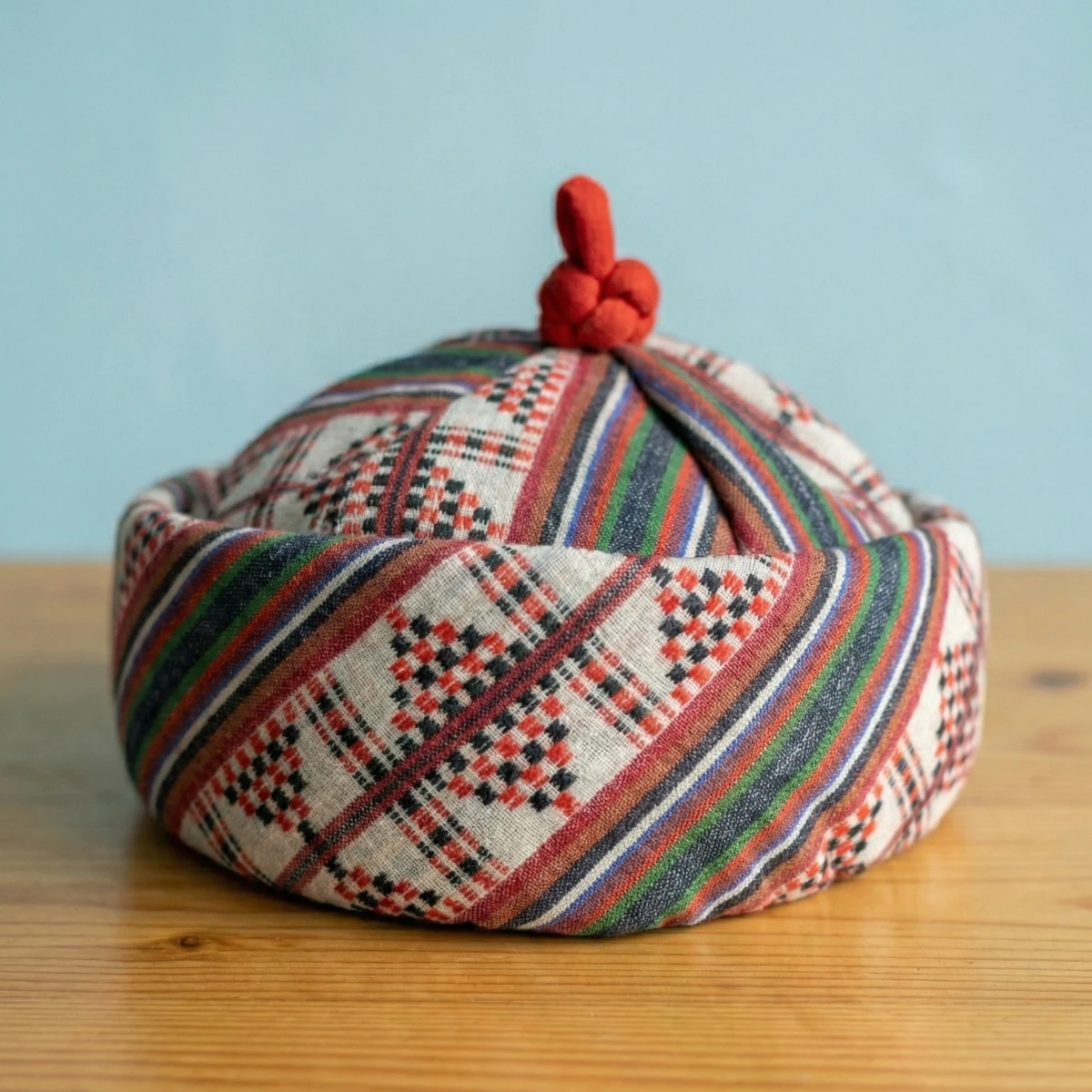 Lepcha Topi woven patterned variant — close view of interlocking geometric weave in maroon, ochre and black
