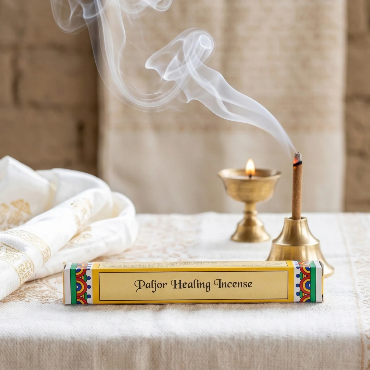 Paljor Healing Incense box front — gold panel with italic script label, traditional Tibetan herbal incense sticks, brass stand and flame