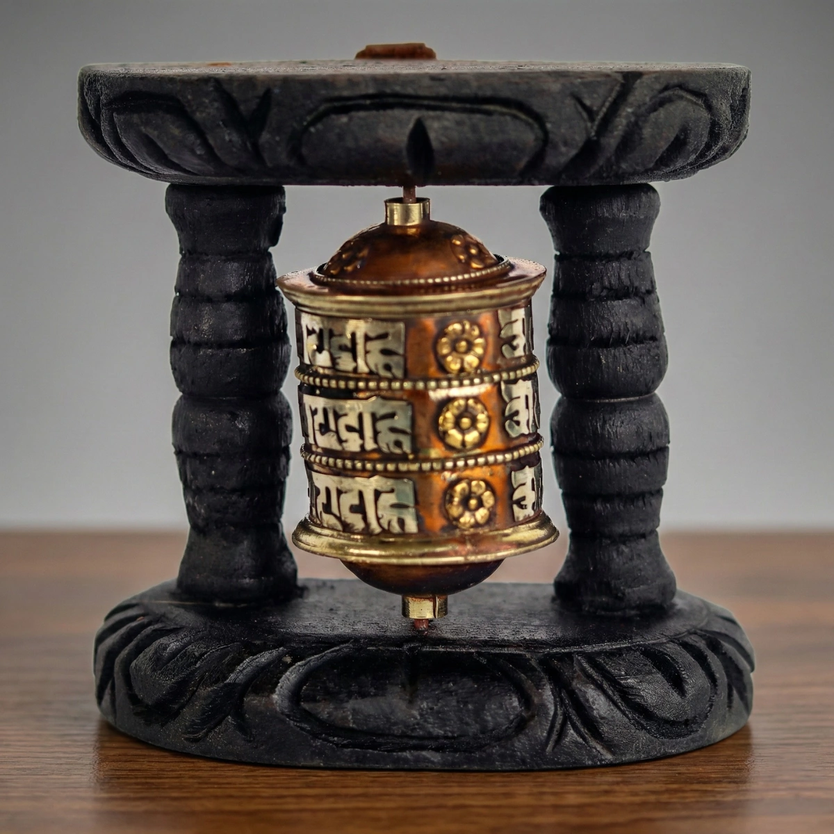 Tibetan prayer wheel front view — three-row Om Mani Padme Hum Uchen script on copper-brass wheel — home altar