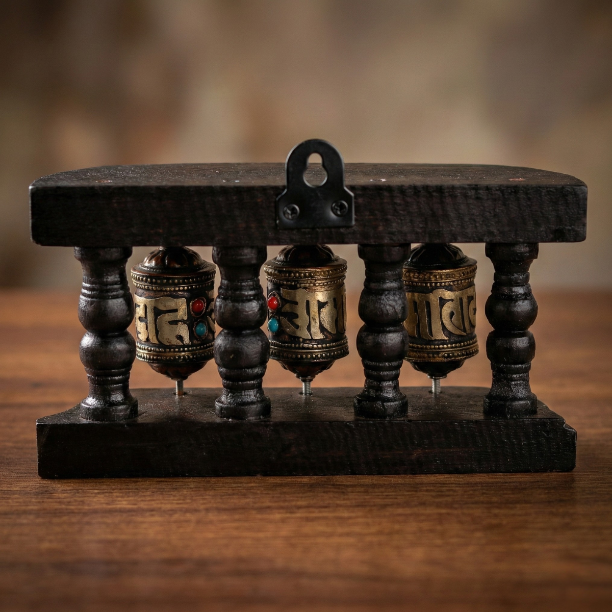 Tibetan prayer wheel set rear view — wall-mount bracket on dark carved wood stand, three brass mantra wheels