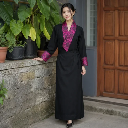 Woman wearing black tibetan chupa dress with magenta damask collar front view
