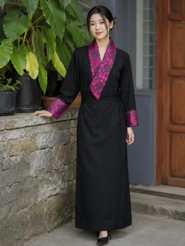 Woman wearing black tibetan chupa dress with magenta damask collar front view