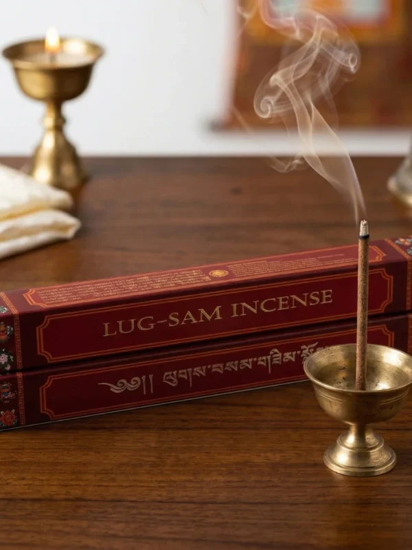 Two Lug-Sam Tibetan herbal incense boxes stacked with burning stick, butter lamp and bell