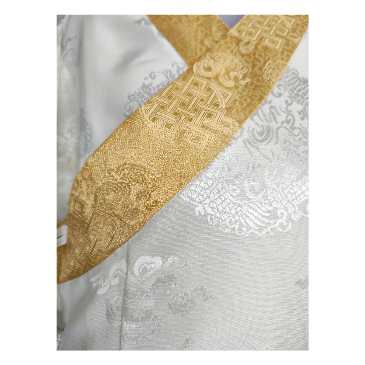 Detail of gold endless-knot border on ivory jacquard bakhu