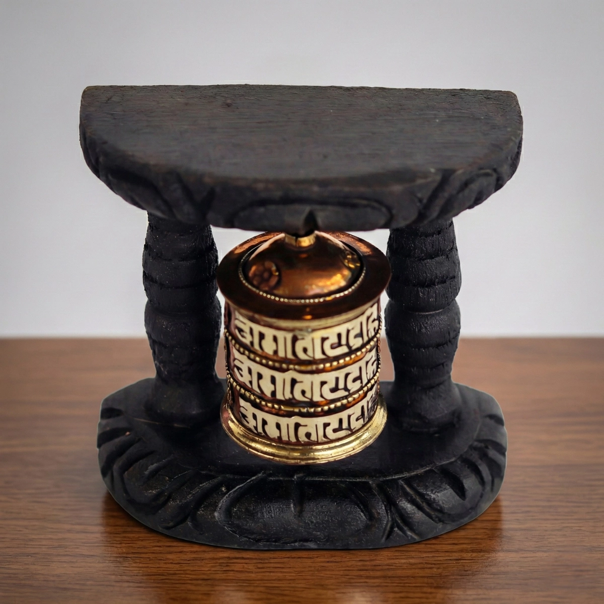 Tibetan prayer wheel on carved black wood stand — brass Om Mani Padme Hum cylinder — table-top altar piece
